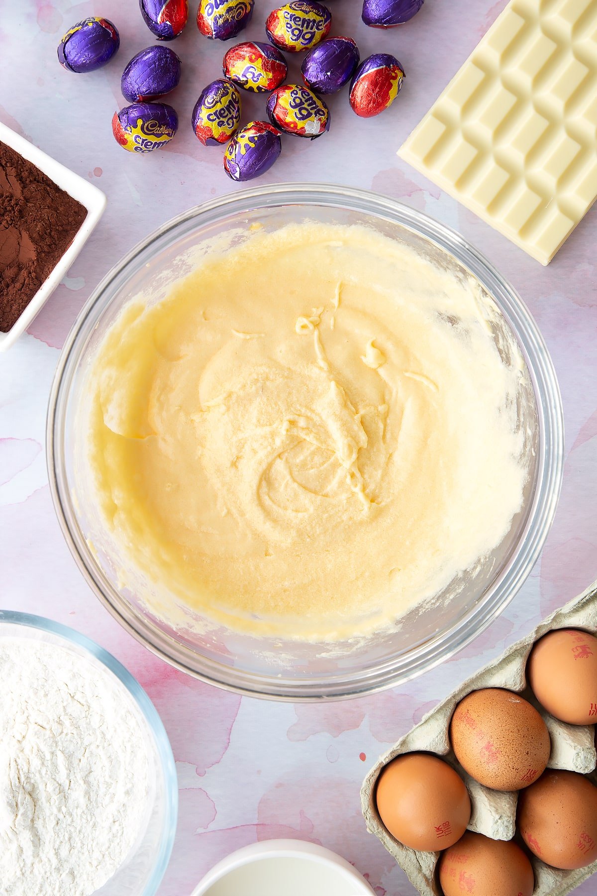 Butter, sugar and eggs beaten together. Ingredients to make Cadbury Creme Egg cakes surround the bowl.