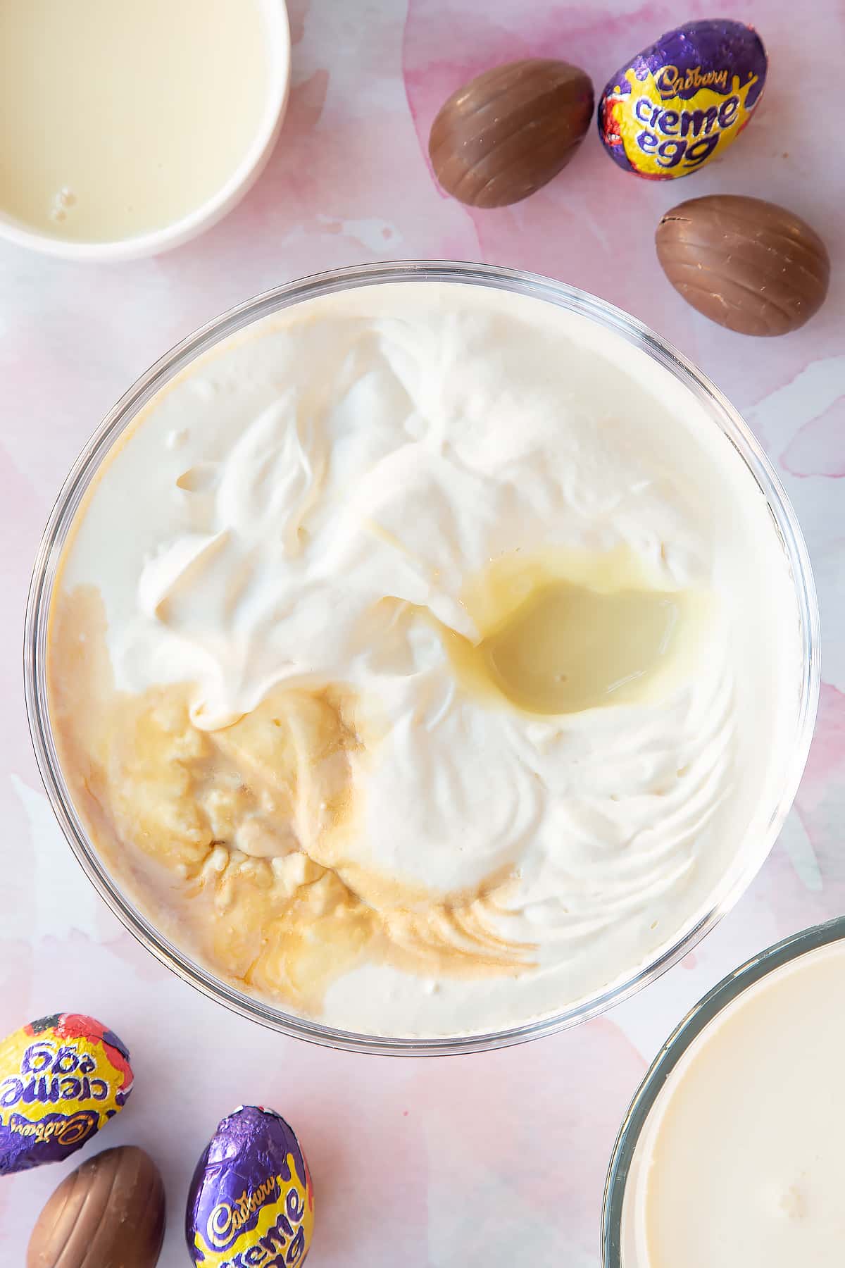 Whipped cream in a bowl with condensed milk and vanilla on top.