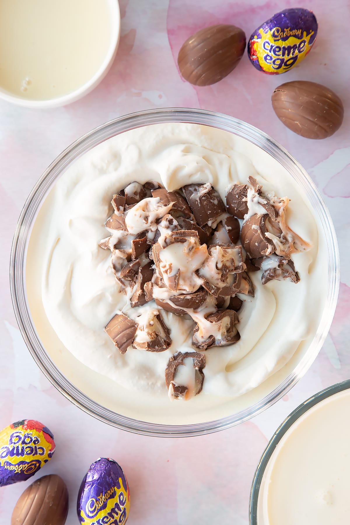 Ice cream mixture in a mixing bowl with chopped Creme Eggs on top.