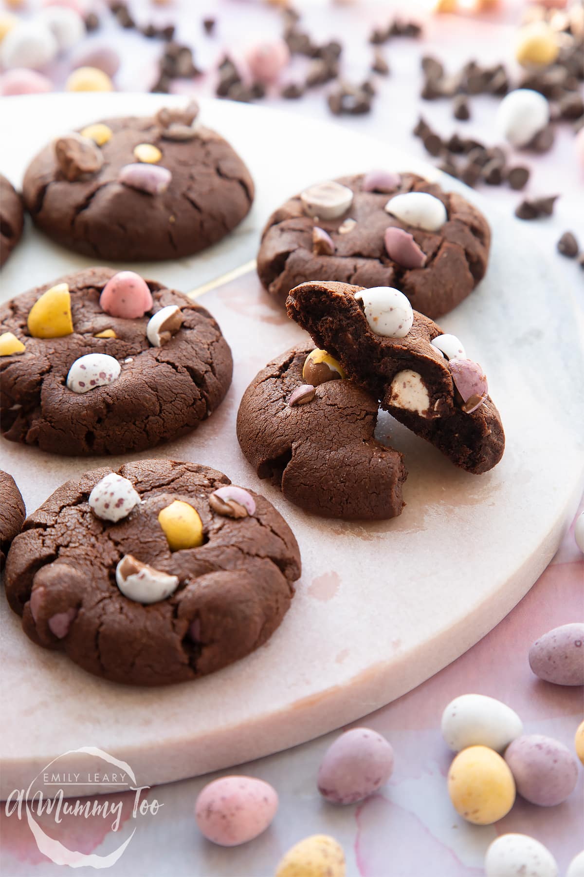 Chocolate Easter cookies arranged on a round marble board. The board is surrounded by Mini Eggs.