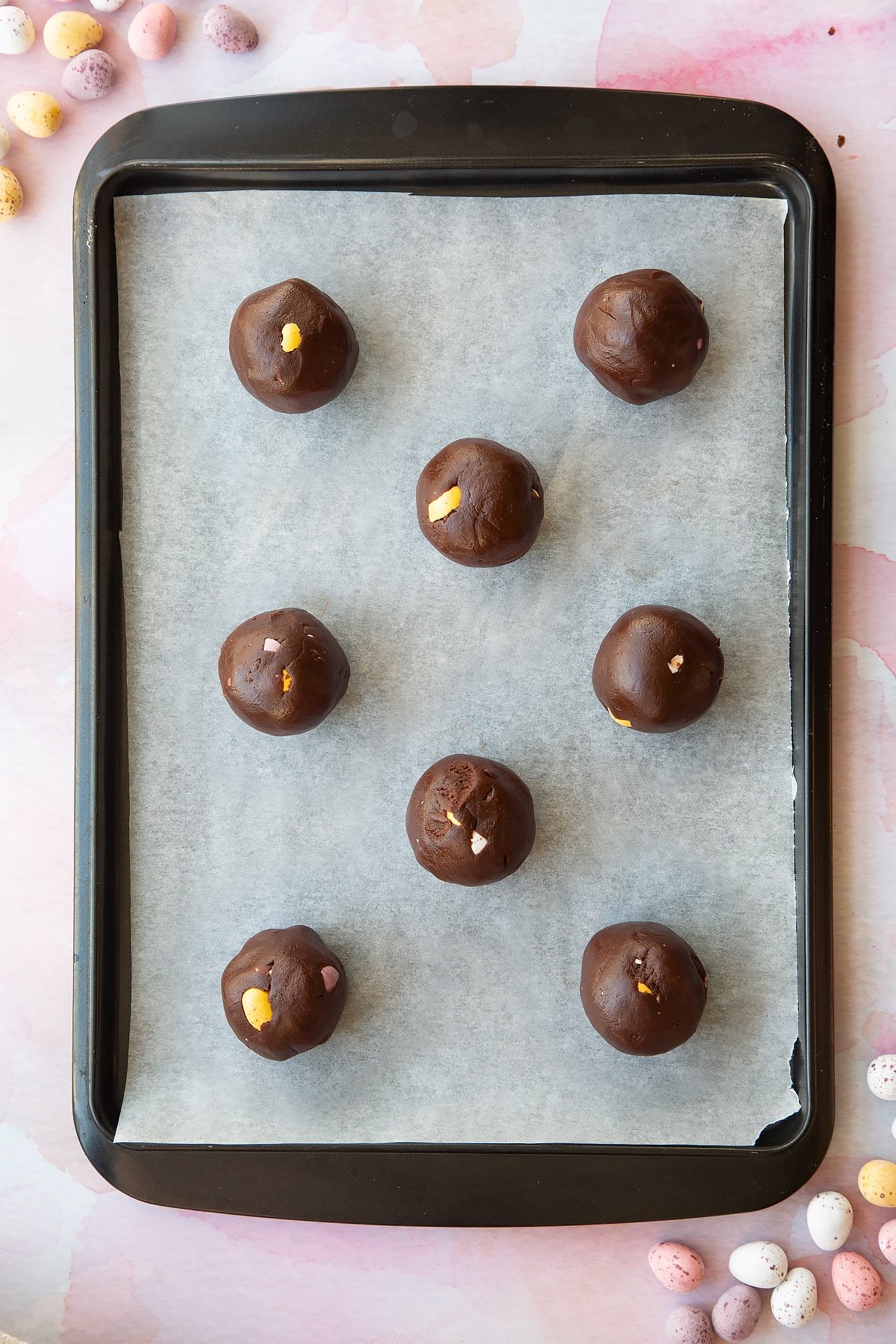 Chocolate Easter cookie dough balls on a tray lined with baking paper.