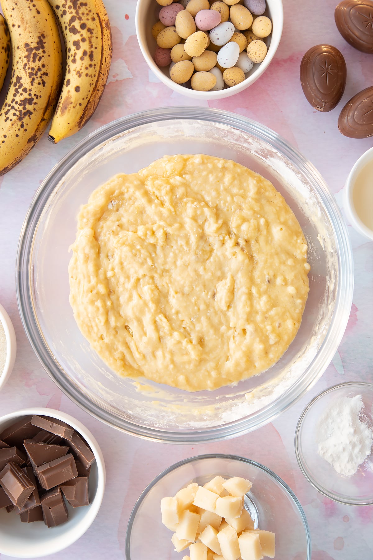 Banana bread batter in a large clear mixing bowl.