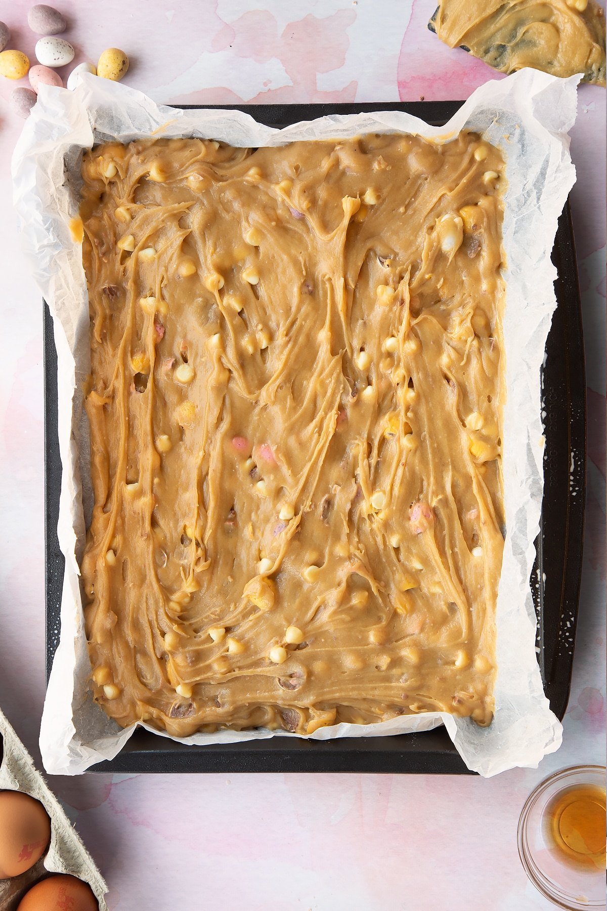 Mini Egg blondie batter in a lined tray. 