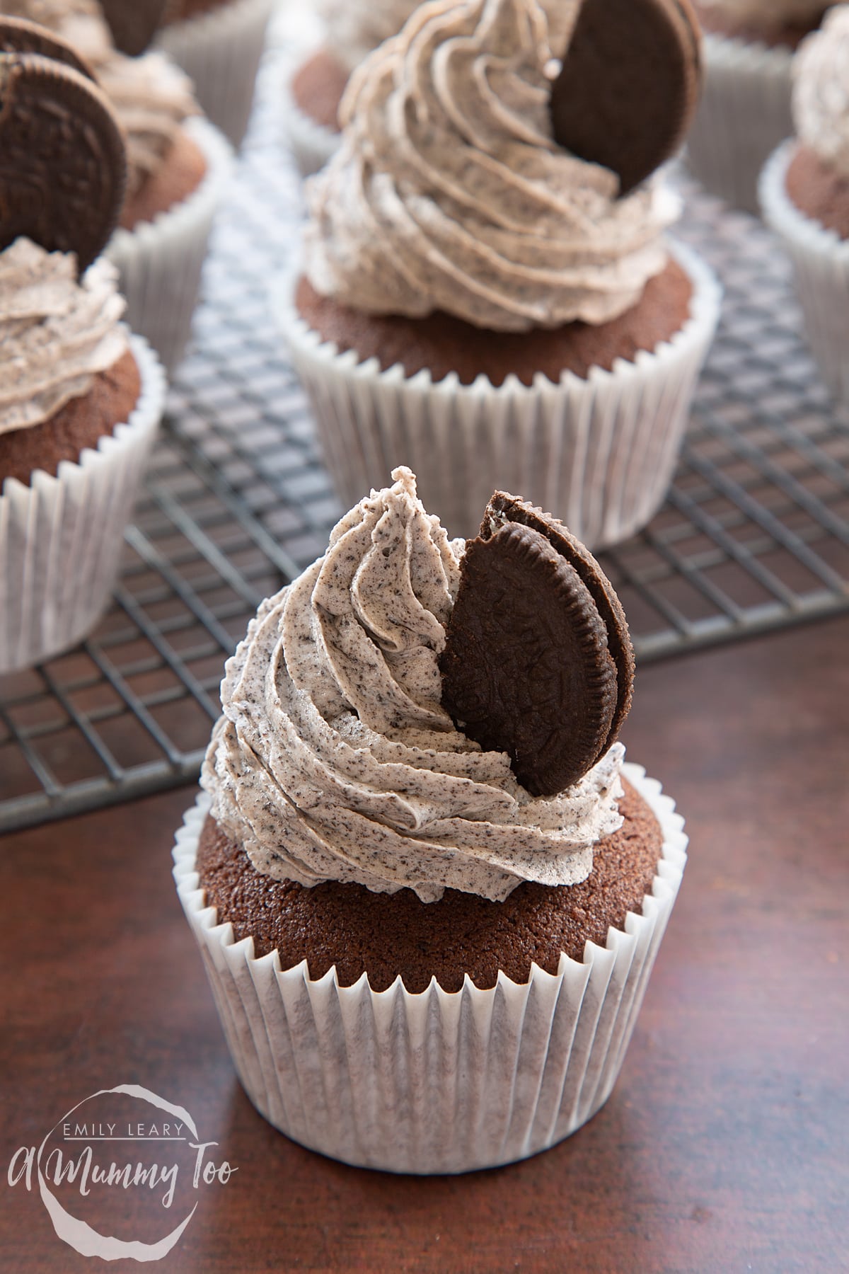 Front view shot of a chocolate cupcaked topped with oreo frosting and half an oreo on the side.