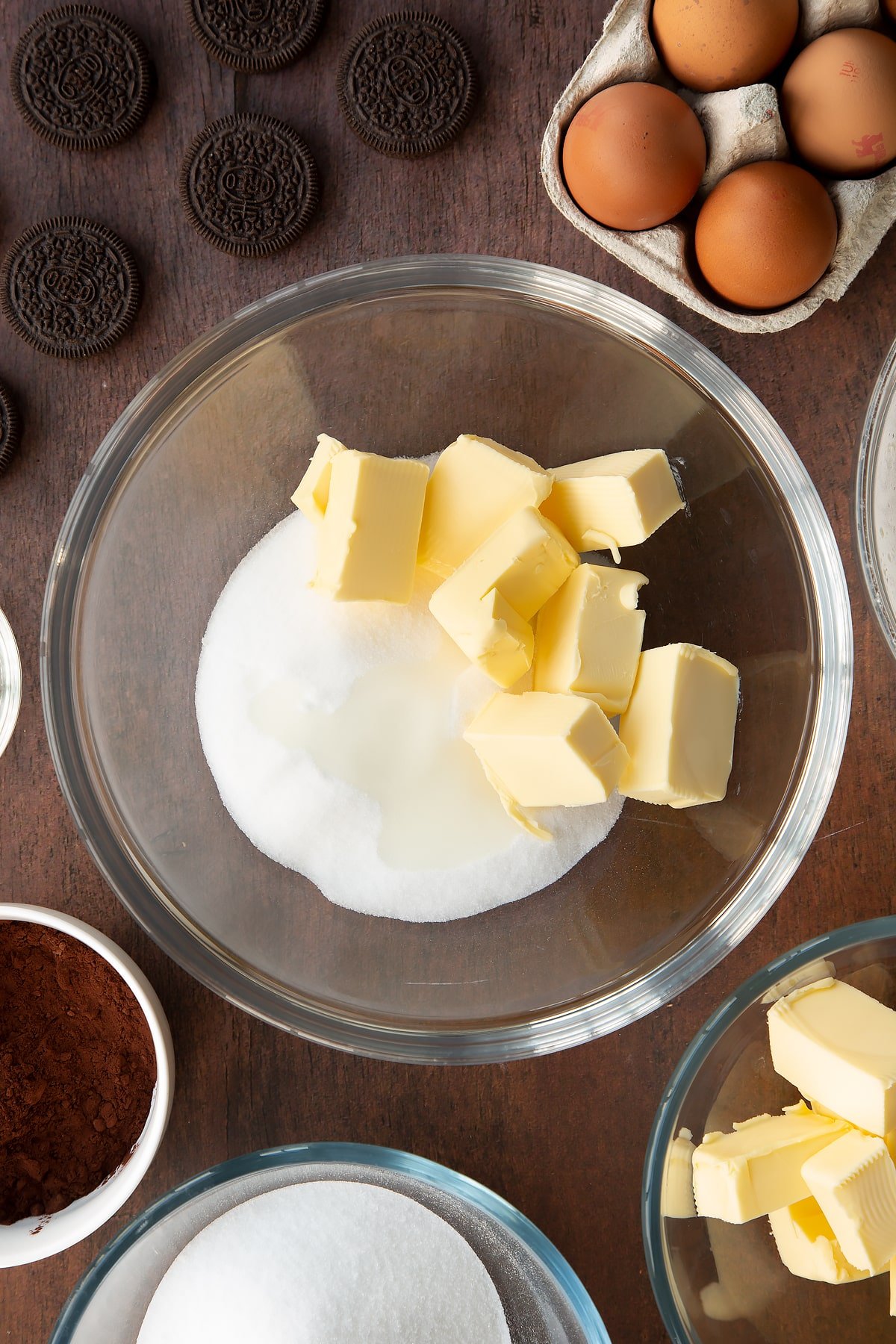 Overhead shot of butter chunks and suagr in a large clear bowl