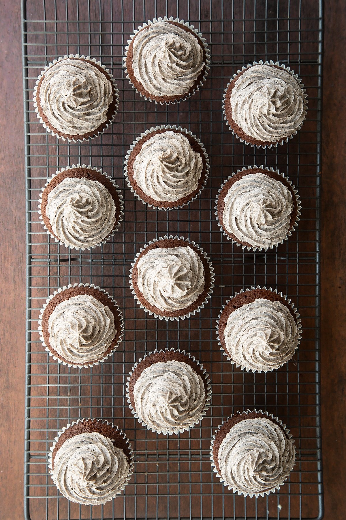 Overhead shot of chocolate cupcakes topped with oreo buttercream on a wire rack