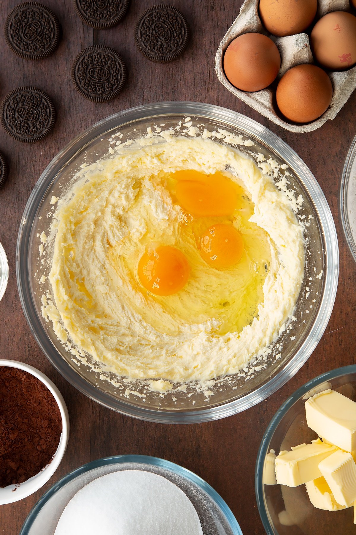 Overhead shot of butter and sugar mix with 3 eggs on top in a large clear bowl