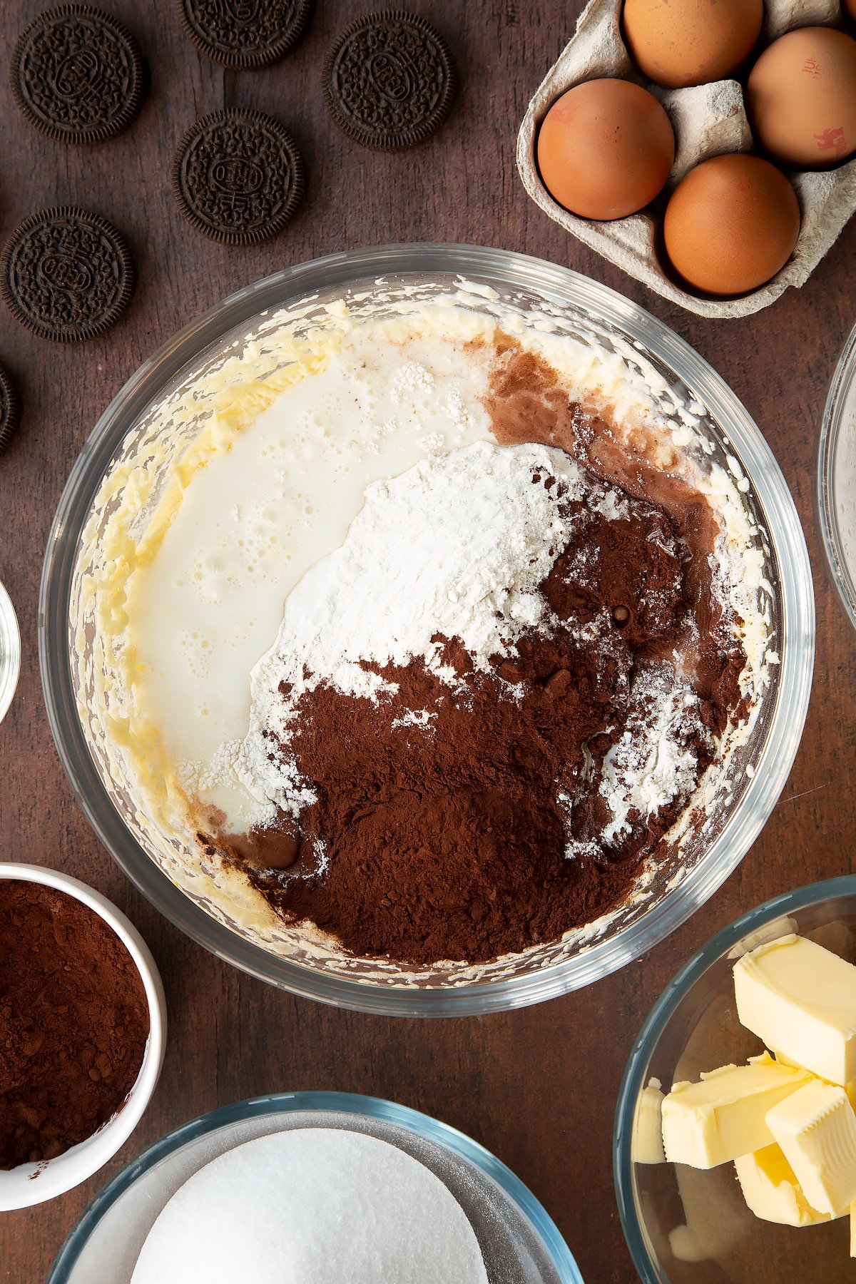 Overhead shot of batter mix with flour, milk, cocoa powder and baking powder in a large clear bowl