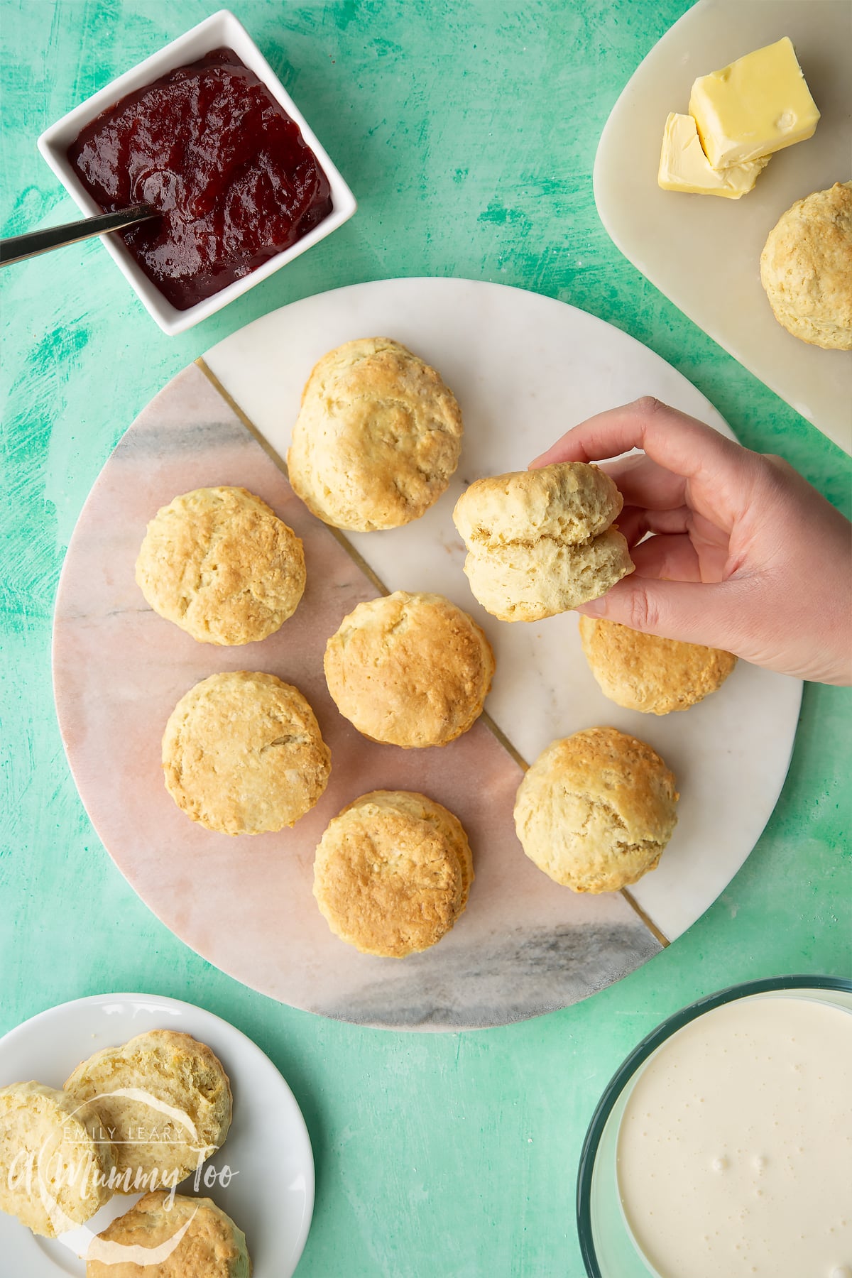 Dairy free scones on a round marble board plate. A hand holds one.