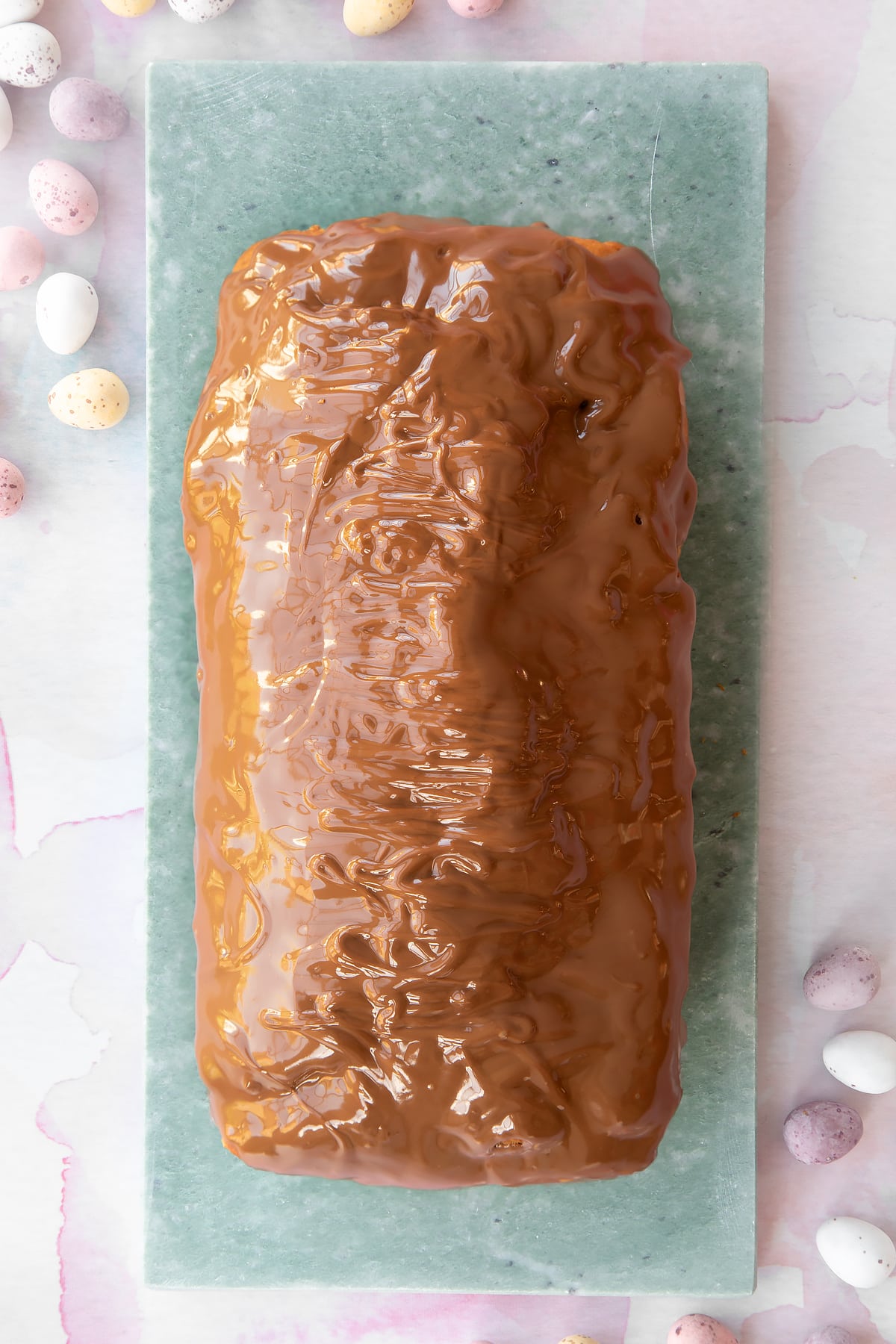Easter banana bread decorated with milk chocolate on a long grey marble board.