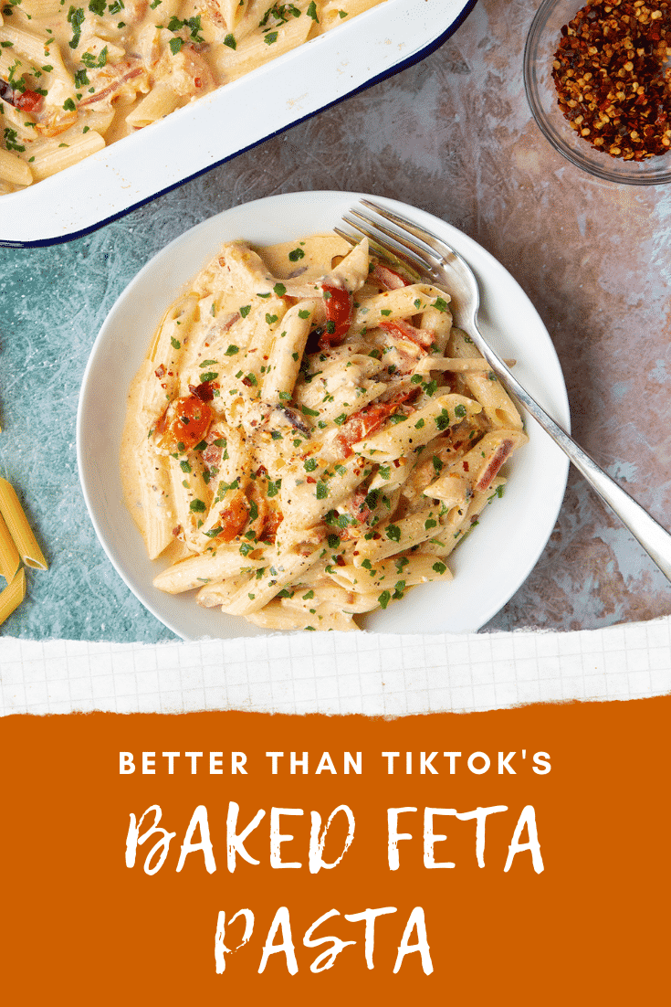 Baked feta pasta in a white bowl, garnished with parsley and chilli flakes. Caption reads: better than TikTok's baked feta pasta 
