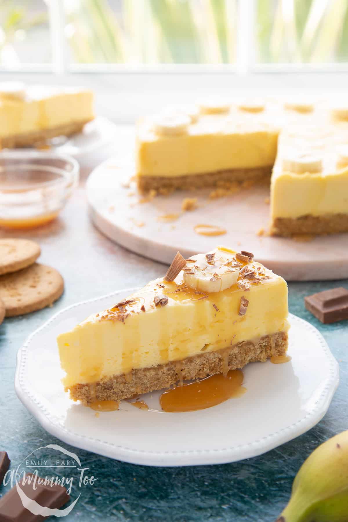 A slice of banoffee pie cheesecake on a white plate. It's drizzled with toffee sauce.