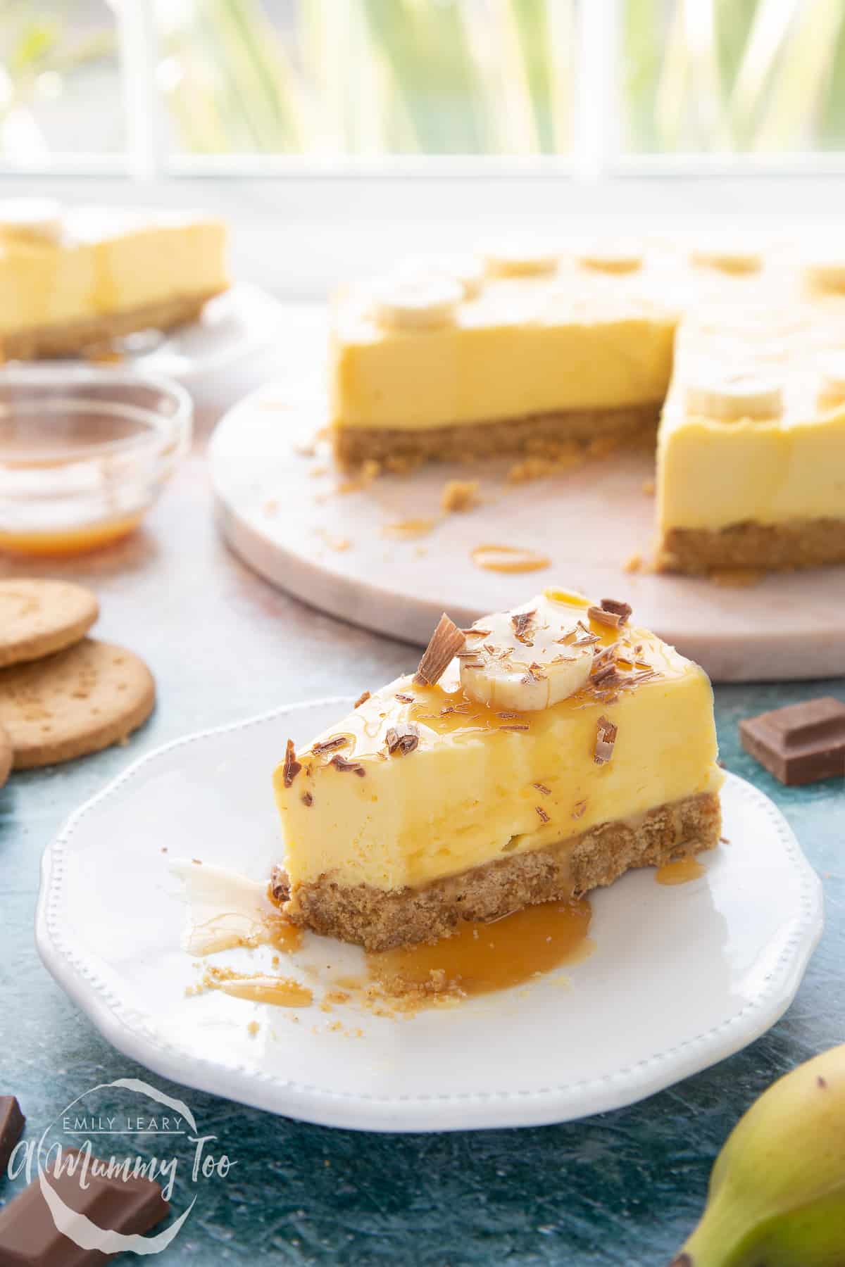 A slice of banoffee pie cheesecake on a white plate. A piece has been eaten.