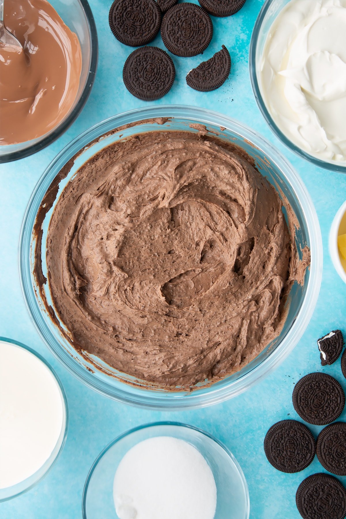 Overhead shot of whipped cheesecake ingredients in a large clear bowl