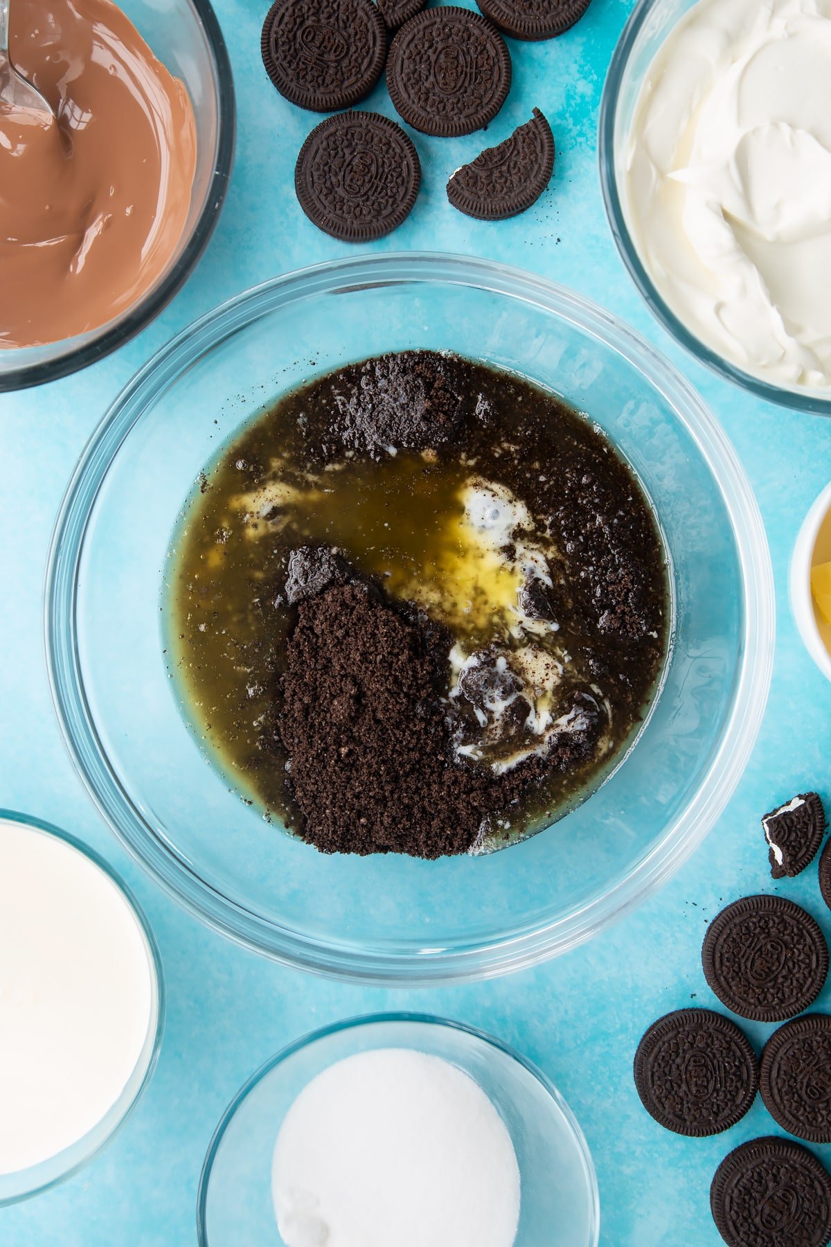 Overhead shot of oreo biscuits crumb with melted butter in a large clear bowl