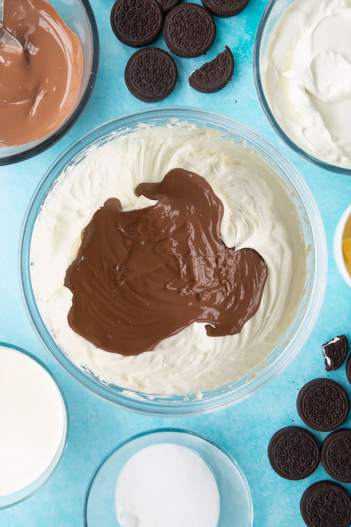 Overhead shot of whipped ingredients with melted chocolate in a large clear bowl