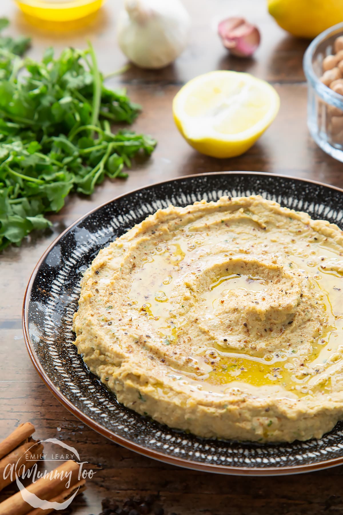 Cinnamon hummus spread in a shallow black and white bowl. It has been seasoned with cinnamon and olive oil