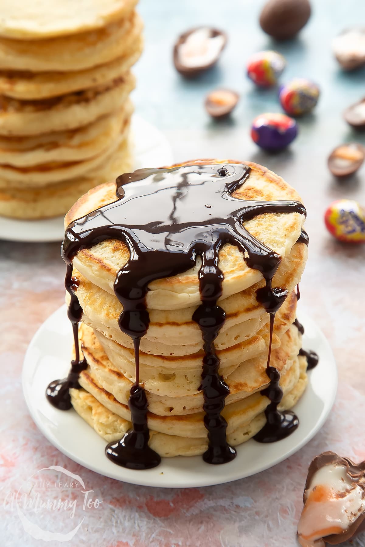 A tall stack of Creme Egg pancakes on a small white plate. The stack is topped with chocolate sauce.