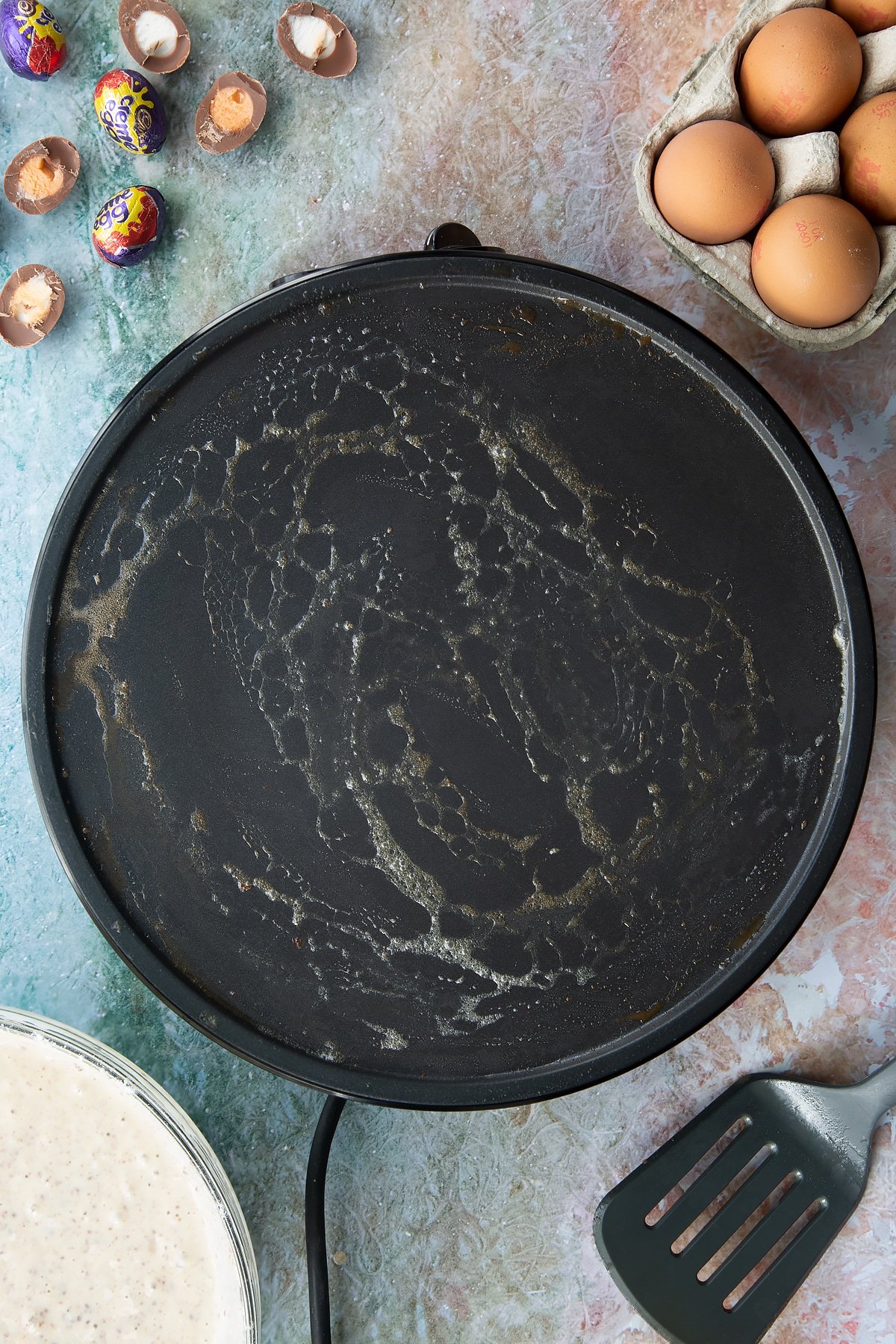 A hot pan with melted butter. Ingredients to make Creme Egg pancakes surround the pan.