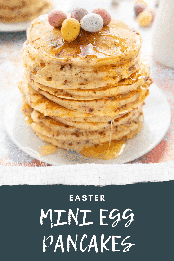 Tall, fluffy Mini Egg pancakes on a white plate in a tall stack. They are drizzled with syrup and topped with Mini Eggs. Caption reads: Easter Mini Egg pancakes