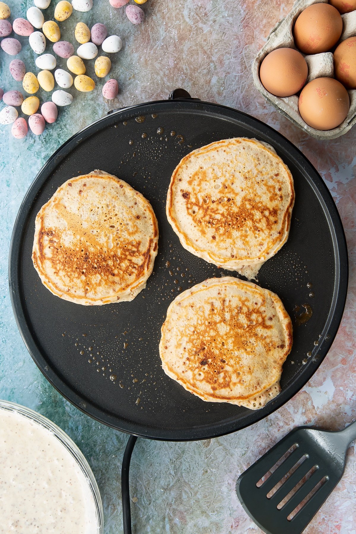 Half cooked Mini Egg pancakes on a hot pan. 