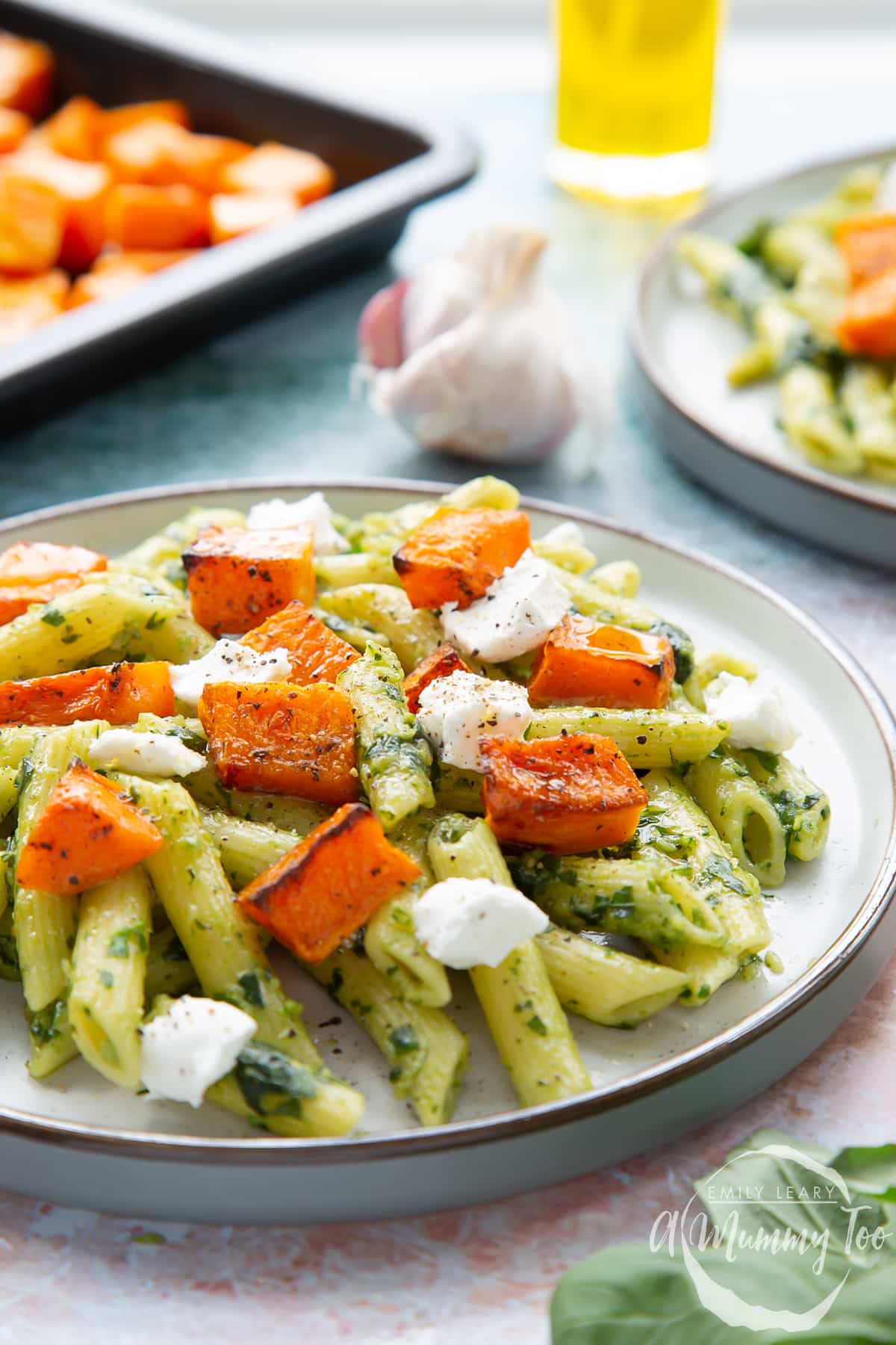 Penne with butternut squash and goat cheese on a grey plate.