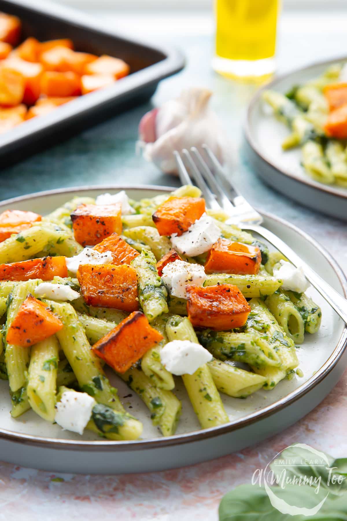 Penne with butternut squash and goat cheese on a grey plate with a fork.