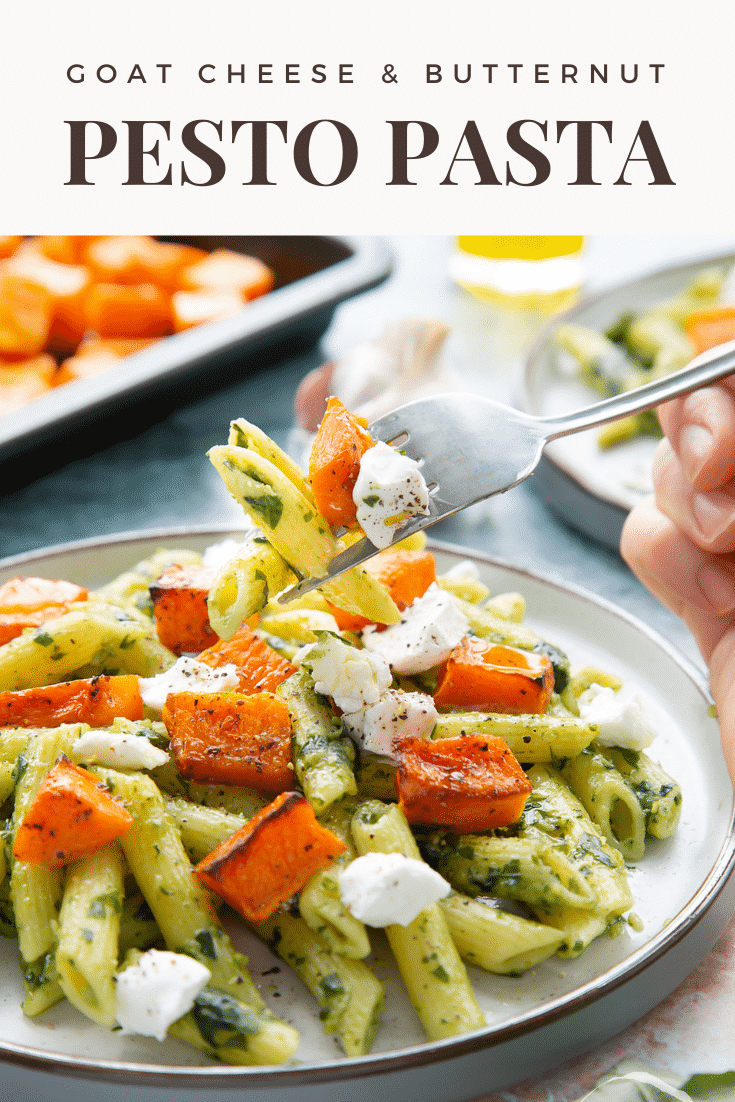 Penne with butternut squash and goat cheese on a grey plate. A hand with a fork takes some. Caption reads: goat cheese & butternut squash pesto pasta
