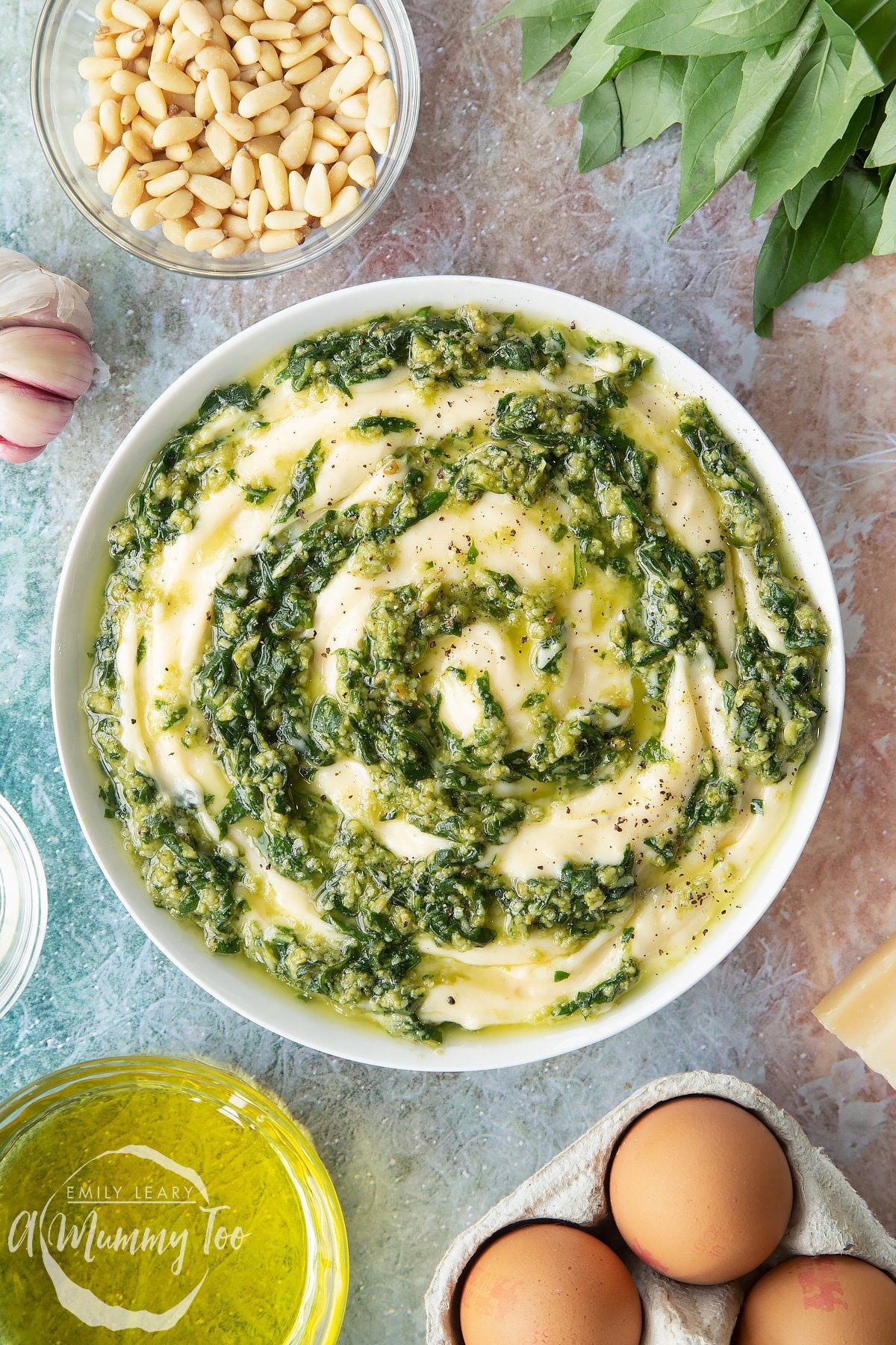 Pesto mayo in a white bowl shown from above. The pesto and mayonnaise are swirled together.