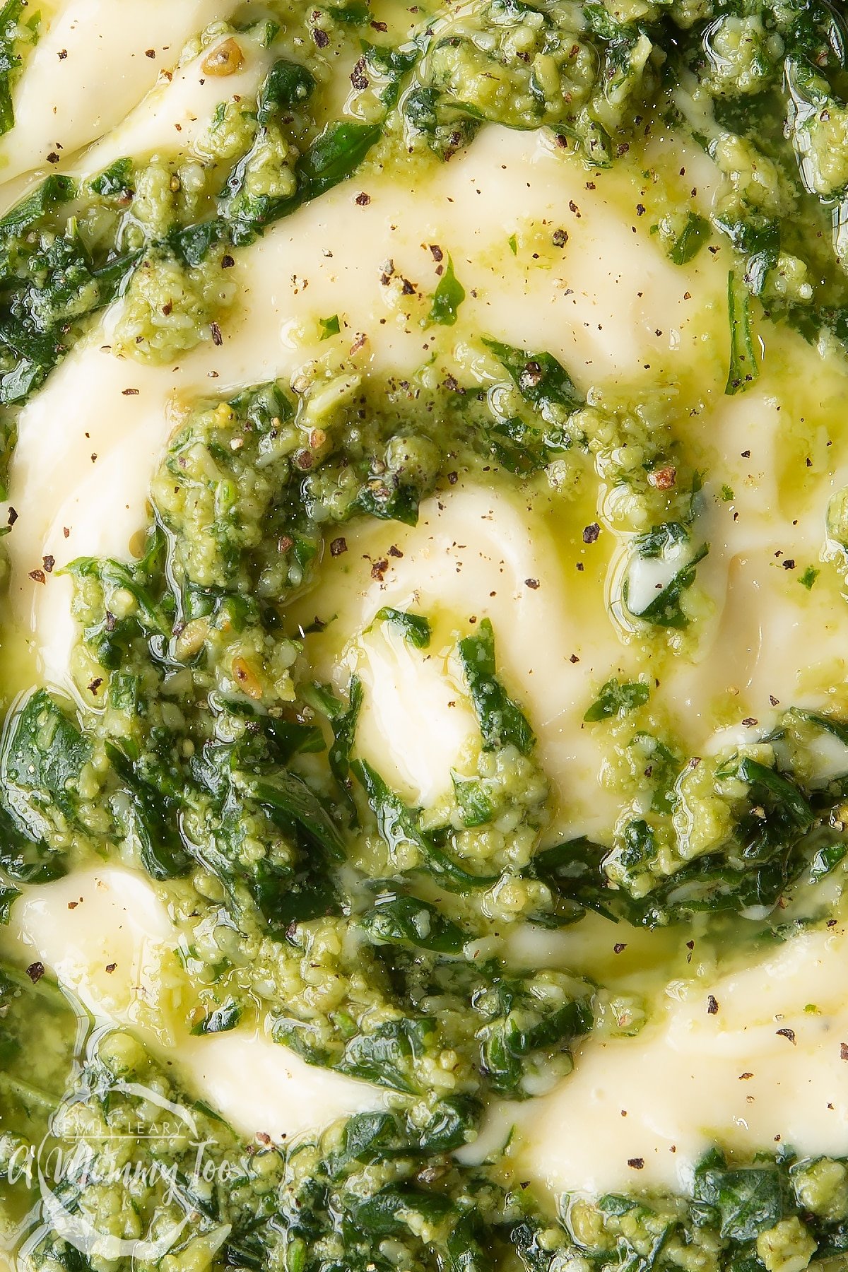 Close up of pesto mayo from above. The pesto and mayonnaise are swirled together. 