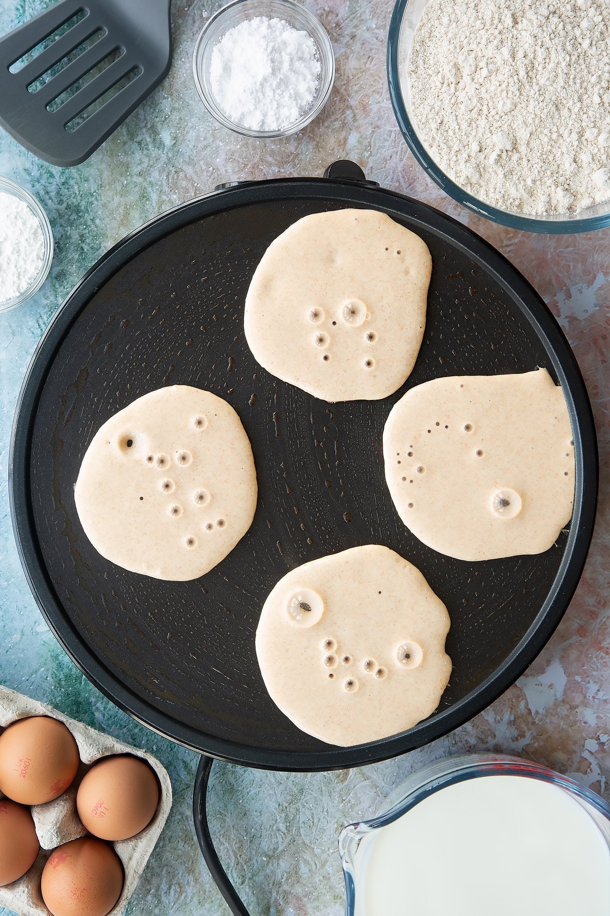 Overhead shot of a hot plate and four circles of batter 