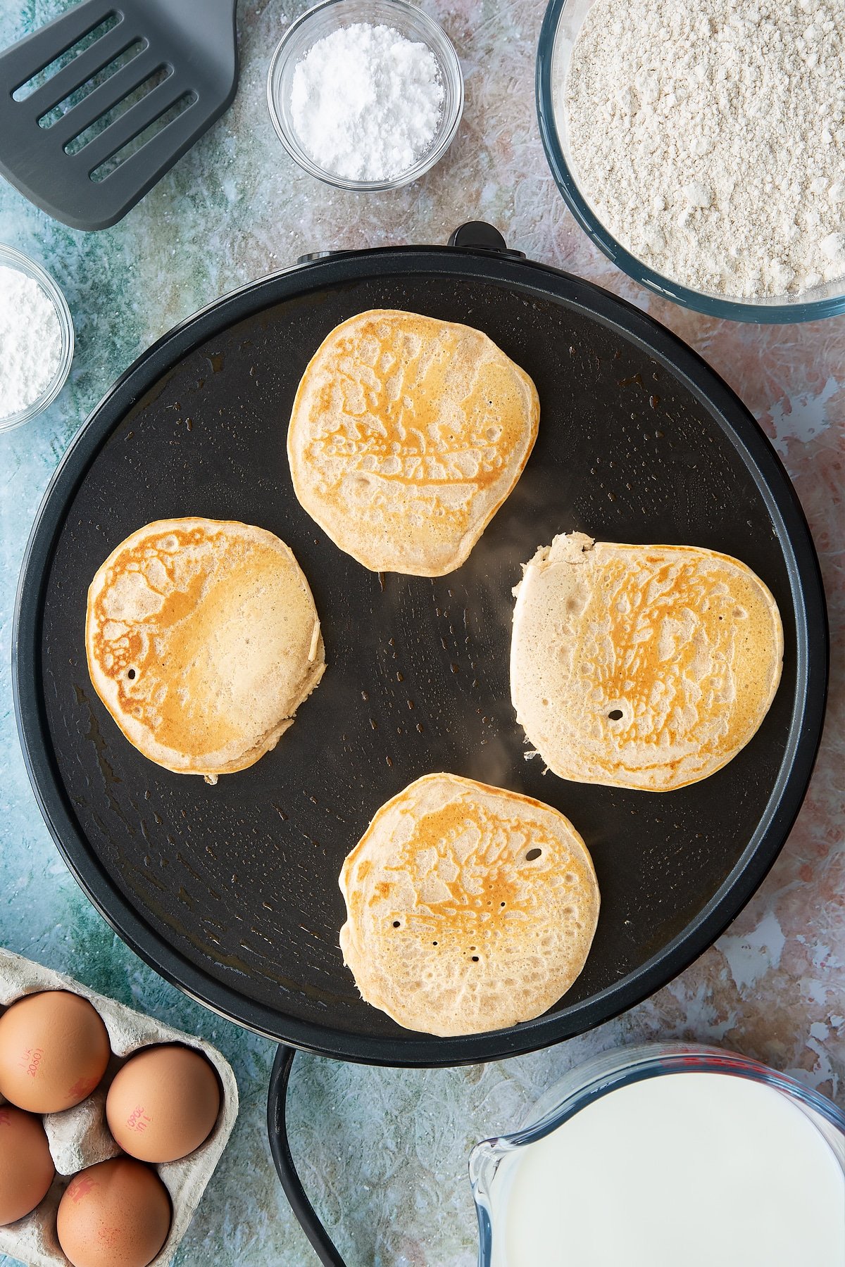 Overhead shot of four pancakes browned on one side