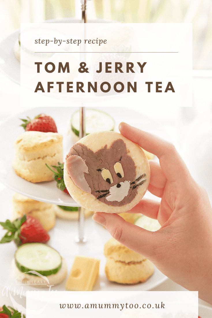 Hand holding a Tom and Jerry sandwhich with a three tier cake stand in the background.