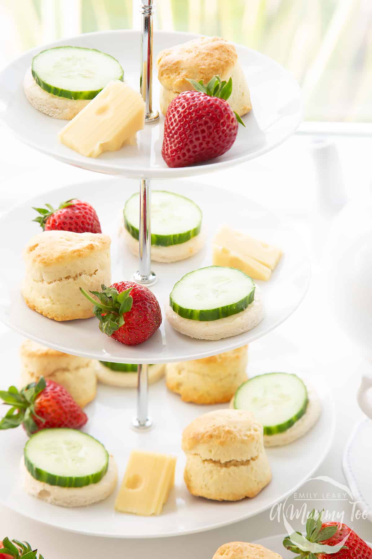 Forward facing shot of the cake platter which has a comibination of scones, sandwhiches and strawberries over three tiers. 