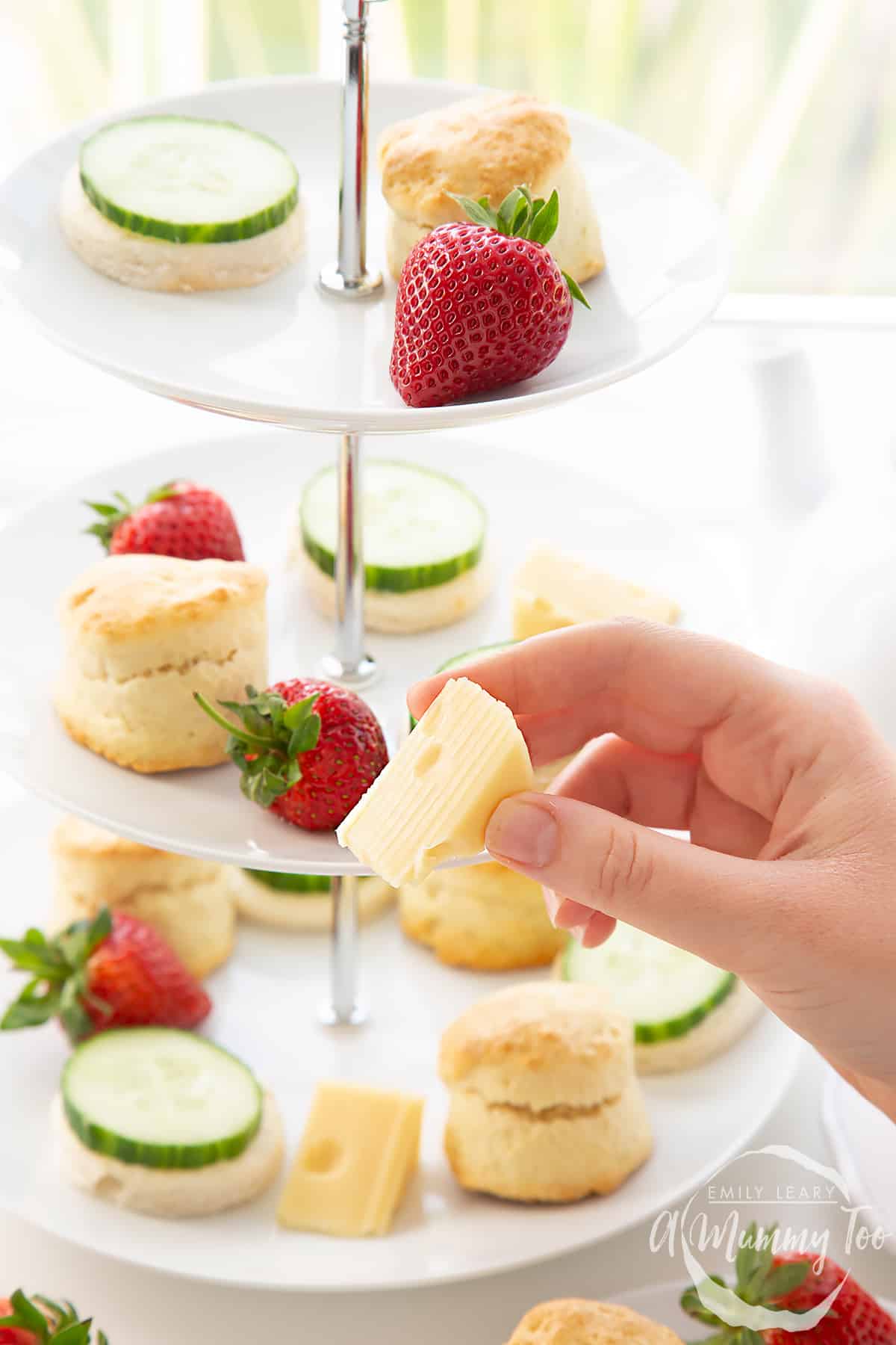 Hand holding a cheese wedge from the Tom and Jerry afternoon tea. 