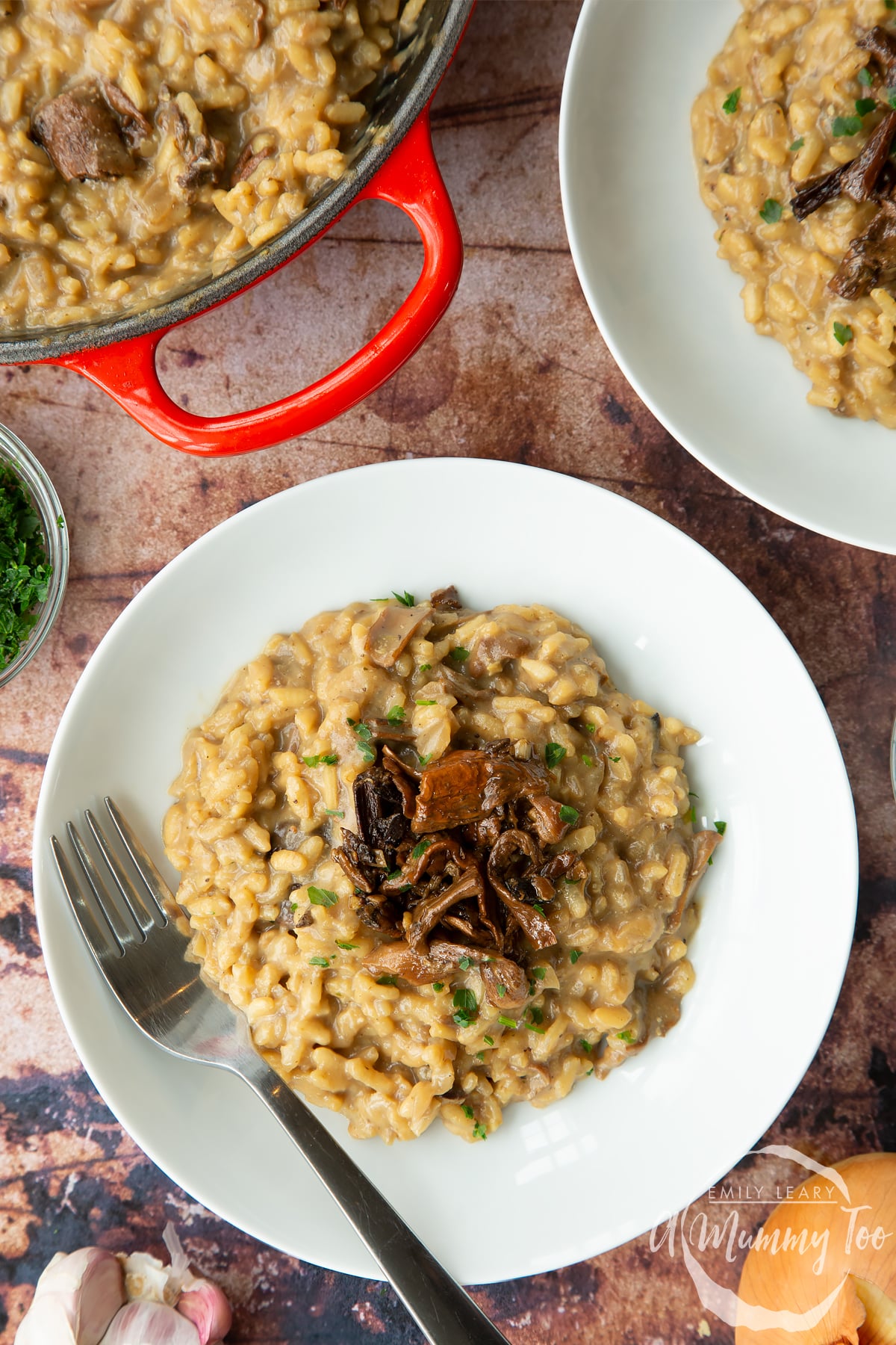 Vegan mushroom risotto in a shallow white bowl with a fork, shown from above.