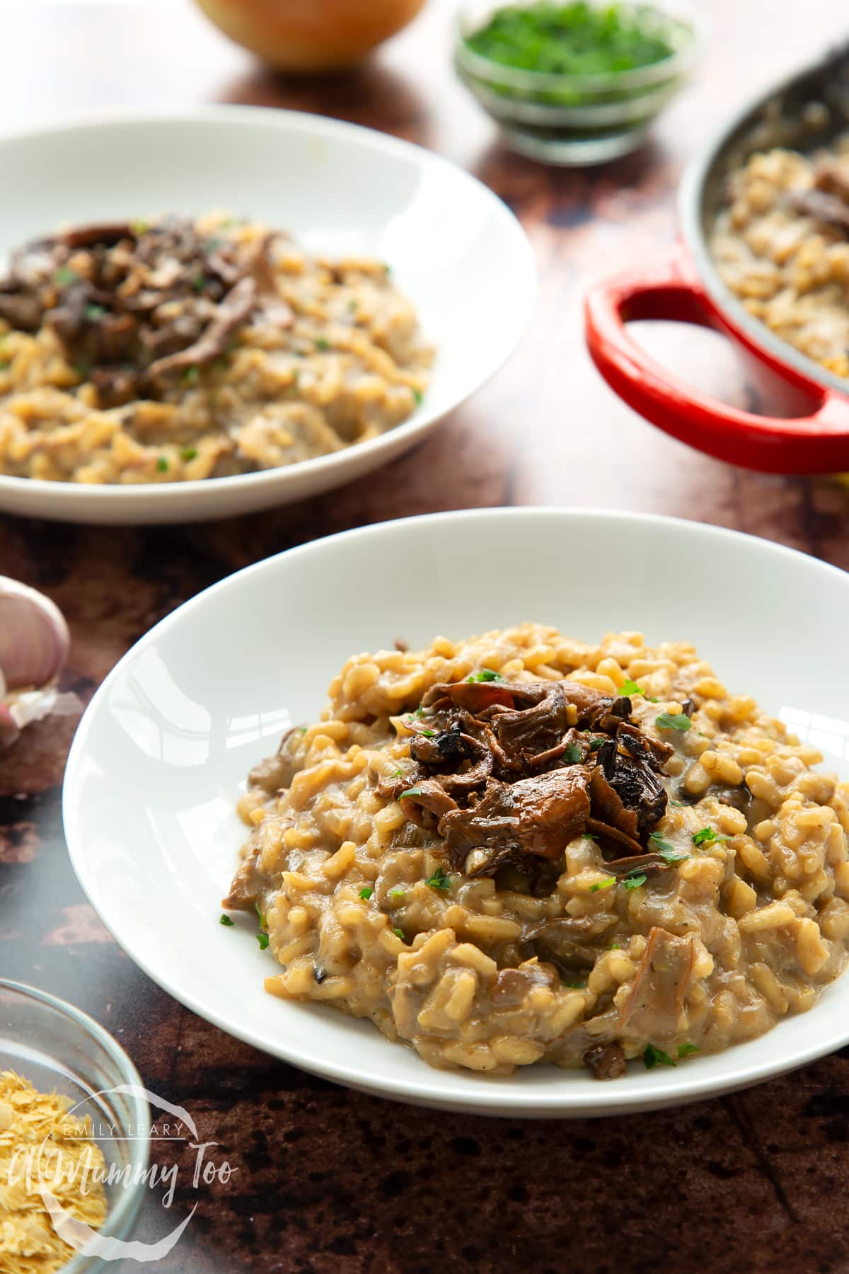 Vegan mushroom risotto in a shallow white bowl, shown from the side.
