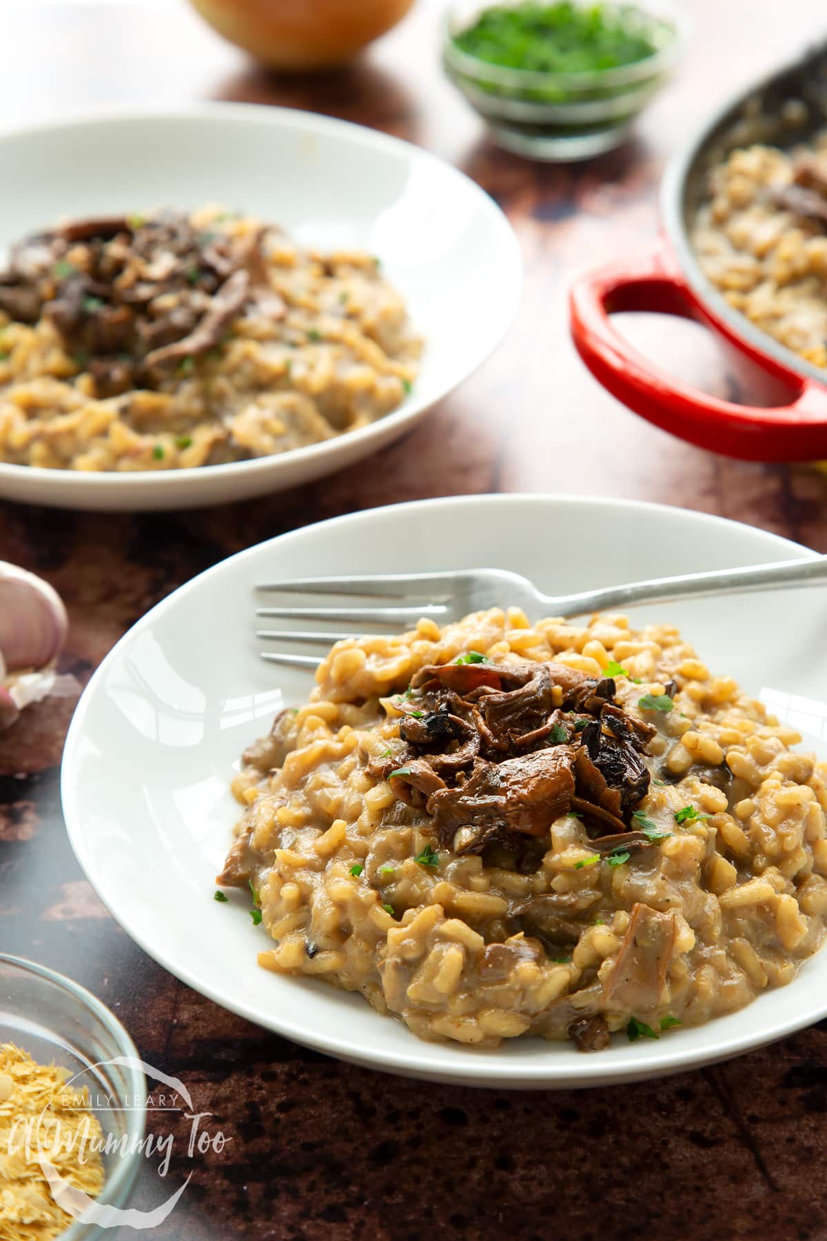 Vegan mushroom risotto in two shallow white bowls with forks.