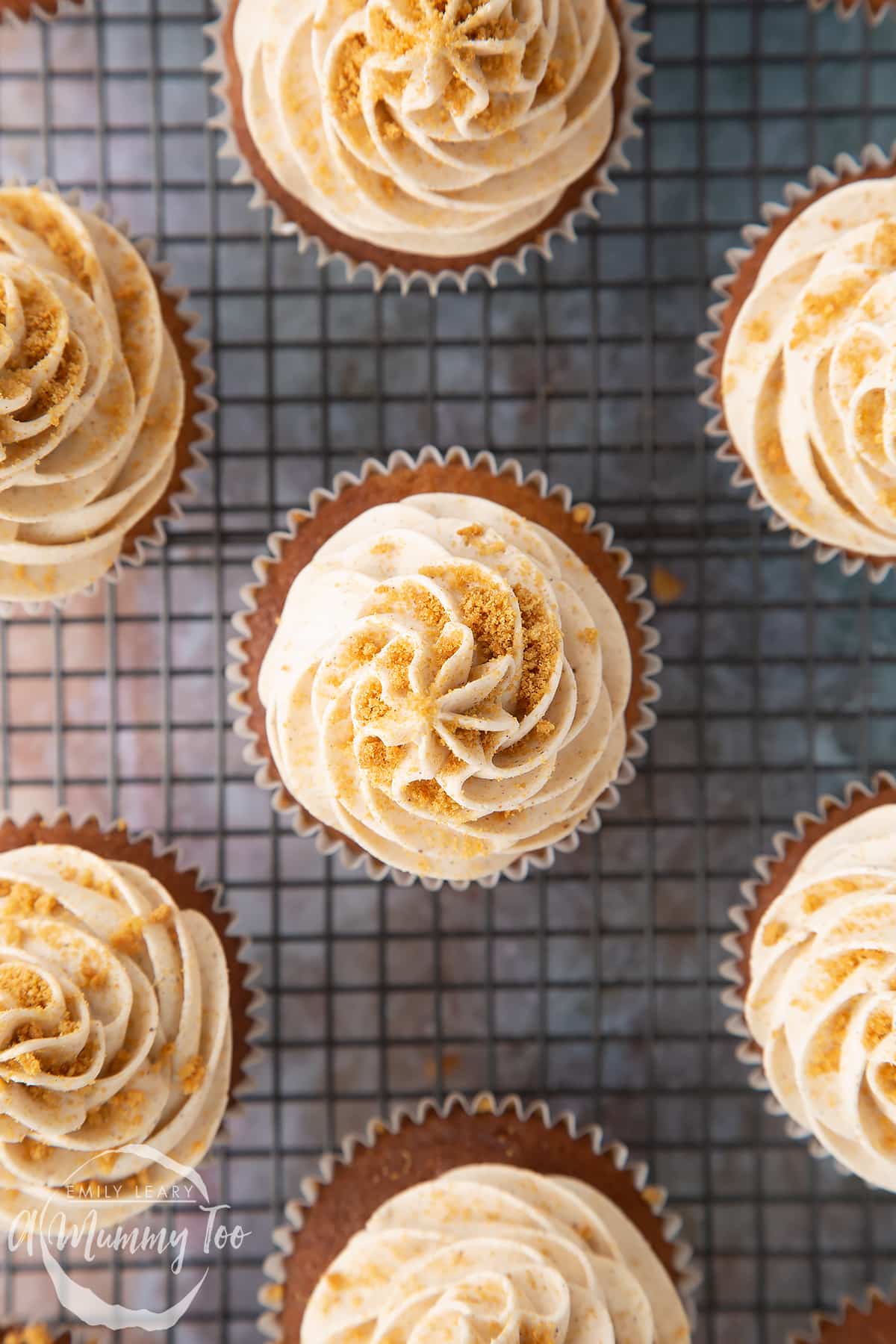 Frosted ginger cupcakes on a wire rack shown from above.