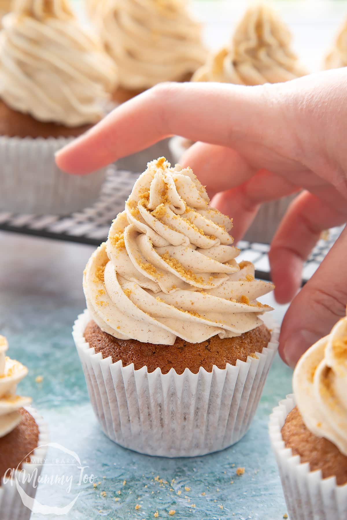 Ginger cupcake on a blue background. A hand reaches for it.