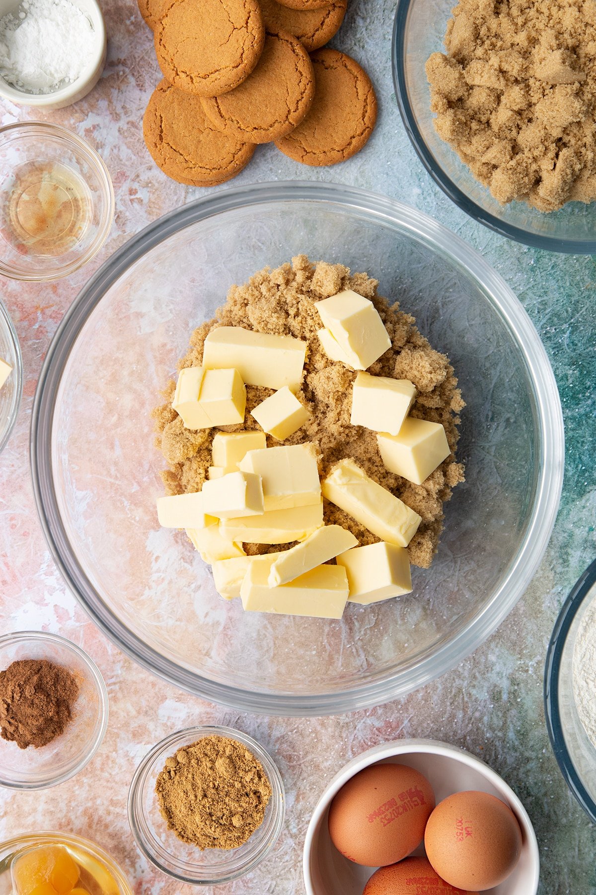 Butter and soft light brown sugar in a mixing bowl. Ingredients to make ginger cupcakes surround the bowl.