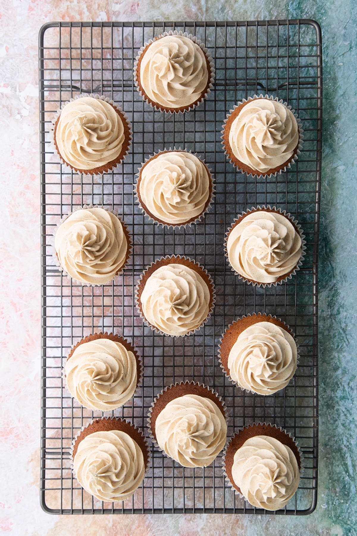 Ginger cupcakes piped with ginger buttercream on a wire rack.