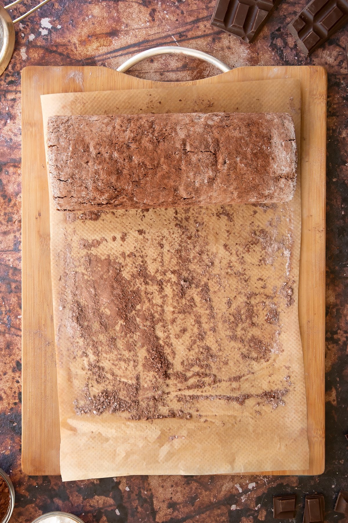 A chocolate Swiss roll filled with chocolate buttercream on a wooden board. 