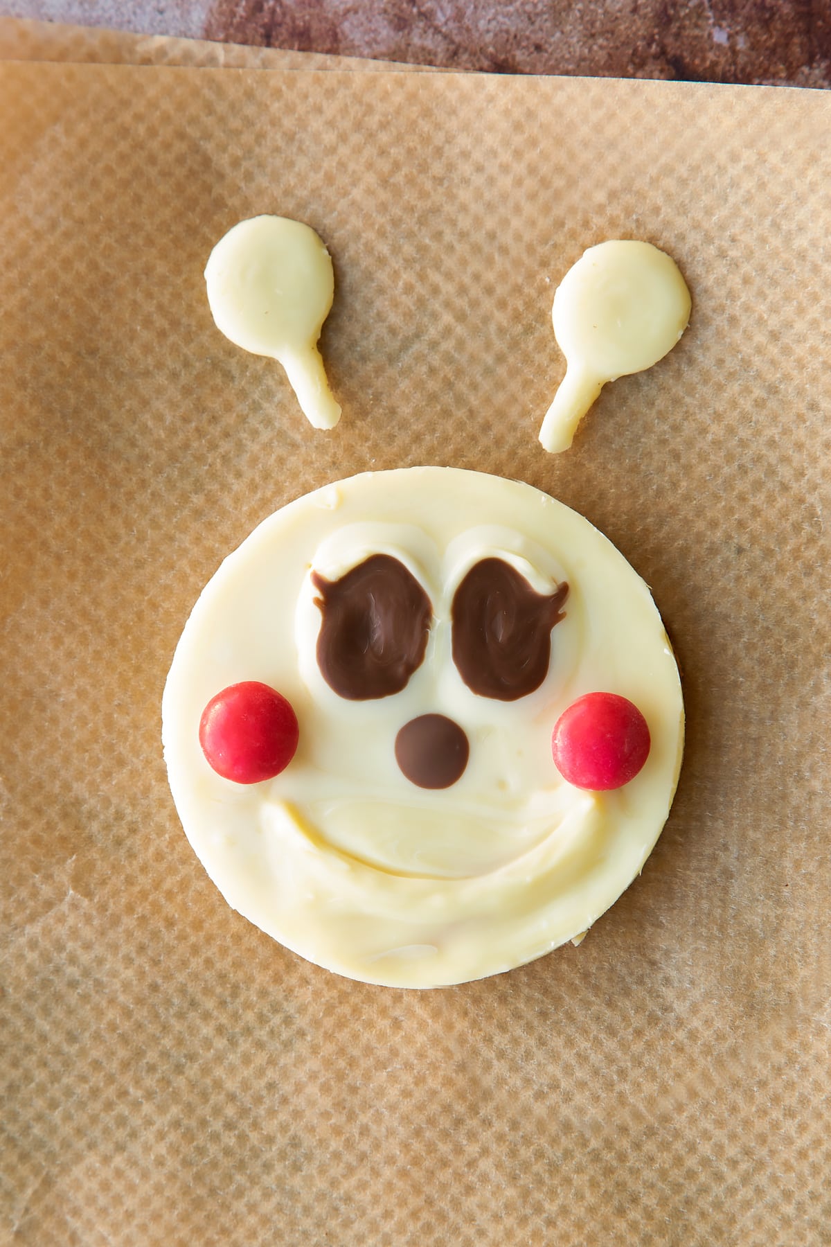 A white chocolate caterpillar face and antennae piped onto baking paper.