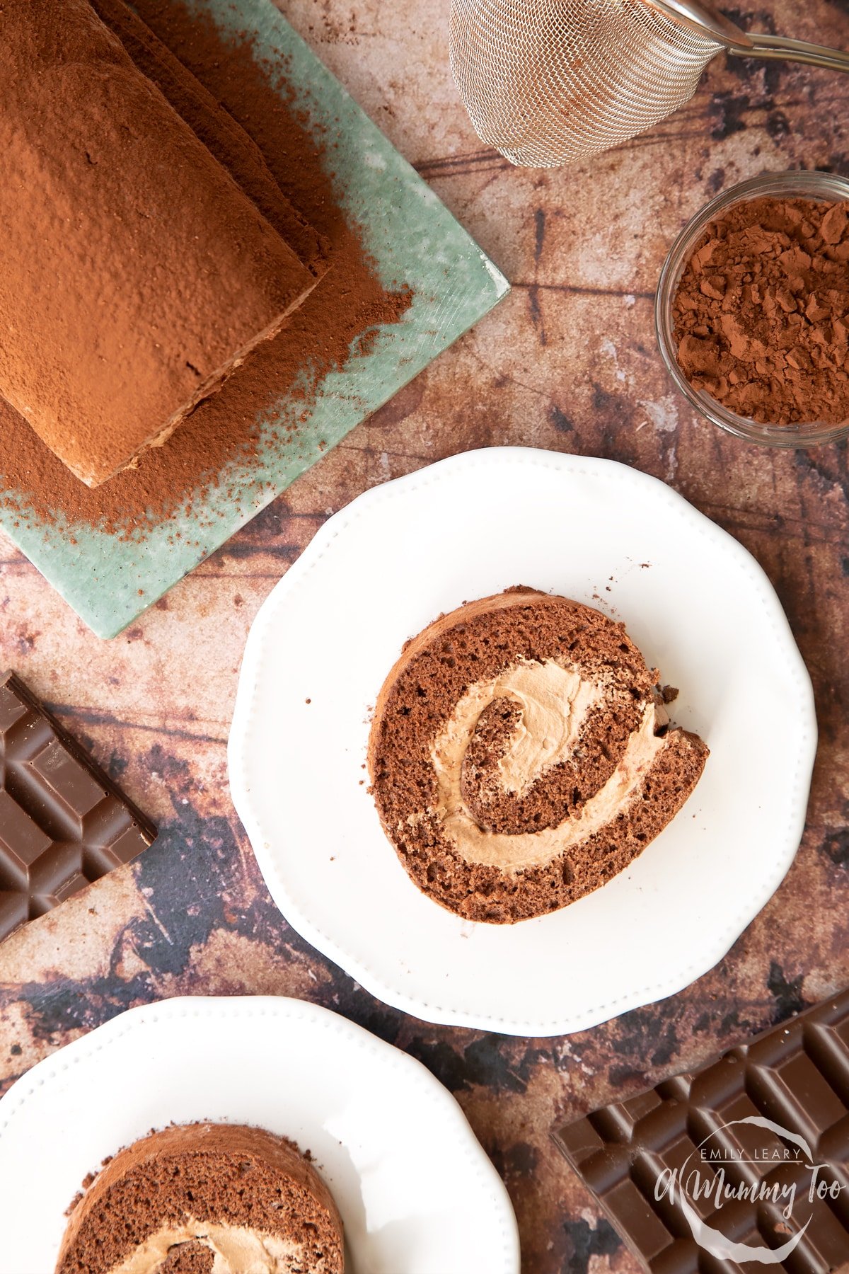 Two slices of Chocolate Swiss roll on white plates, shown from above.