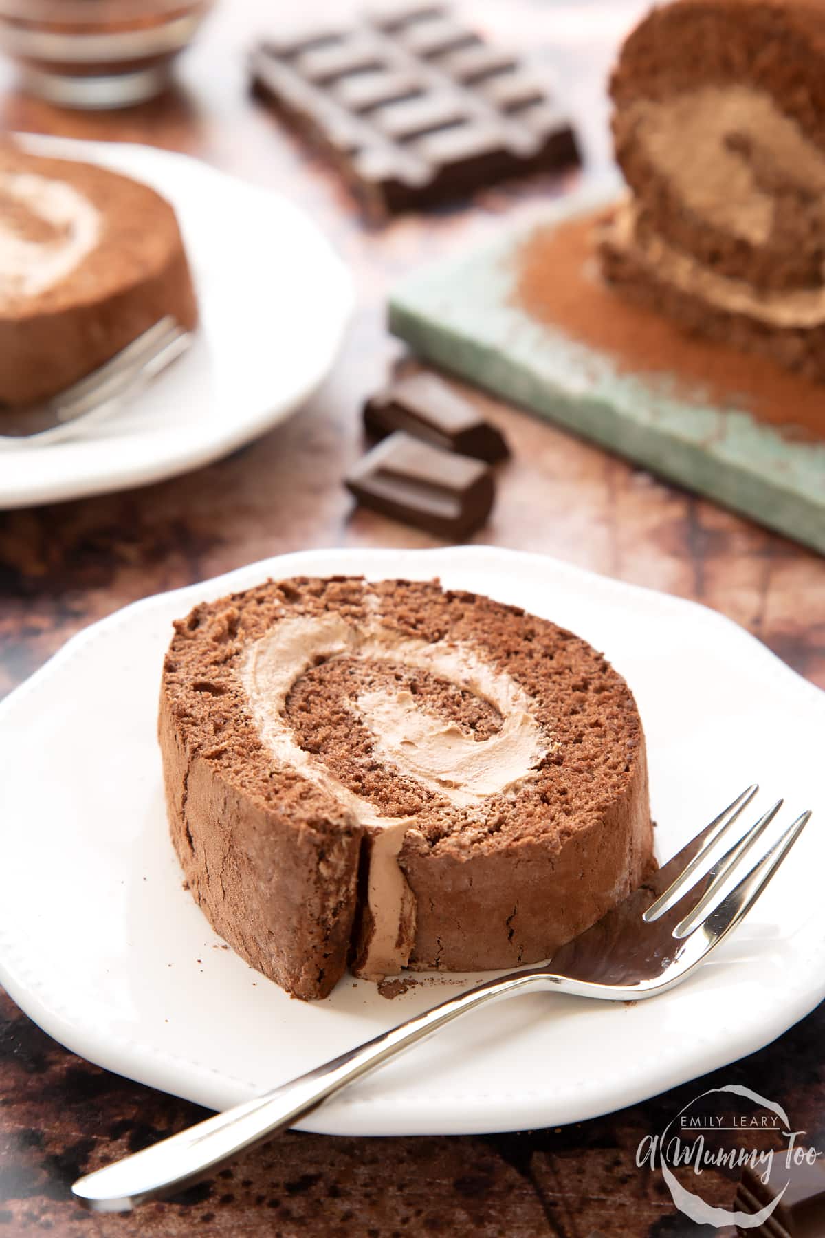 A slice of Chocolate Swiss roll on a white plate with a fork.