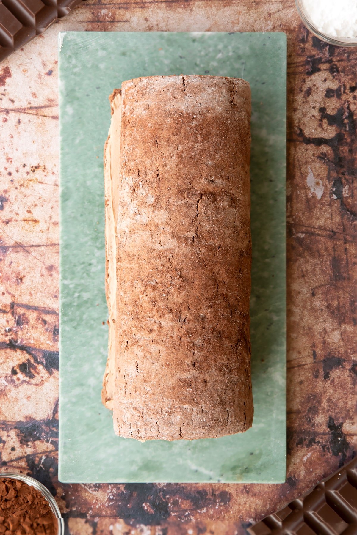 A Chocolate Swiss roll on a grey marble board.