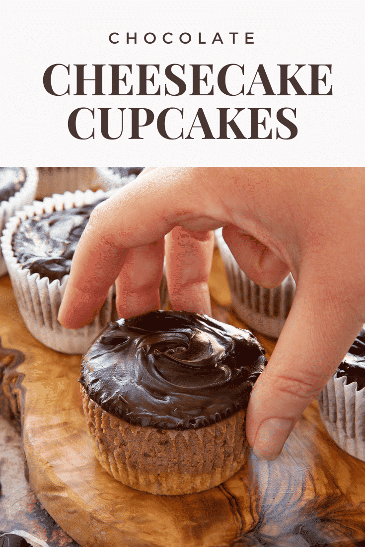 Chocolate cheesecake cupcakes in rows on an olive wood board. A hand reaches for one. Caption reads: Chocolate cheesecake cupcakes