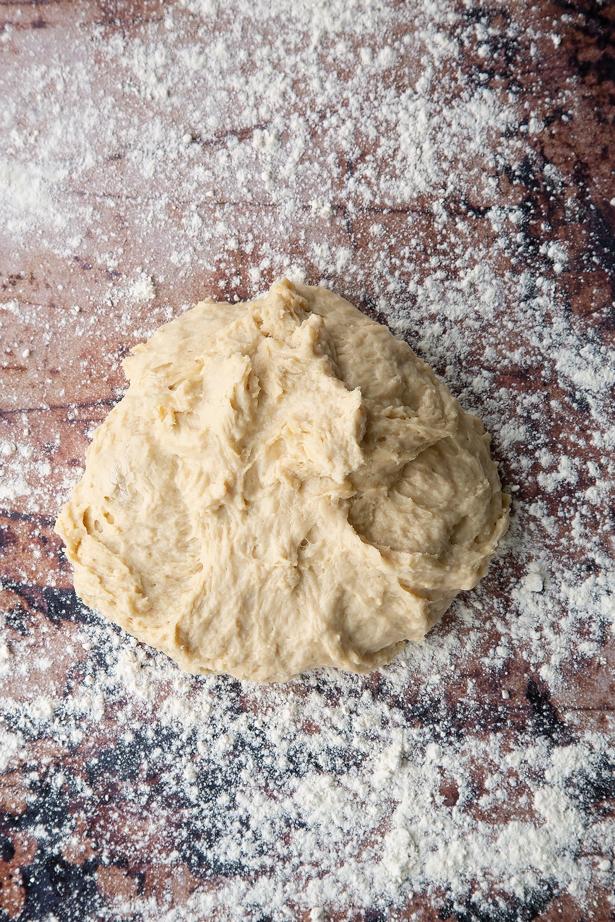 Overhead shot of sticky white dough on a floured surface