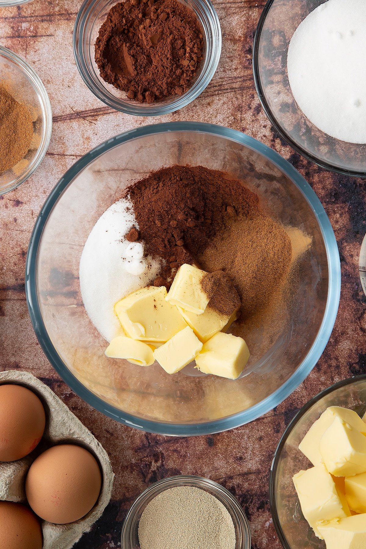 Over head shot of cinnamon, sugar, butter and cocoa in a large clear bowl